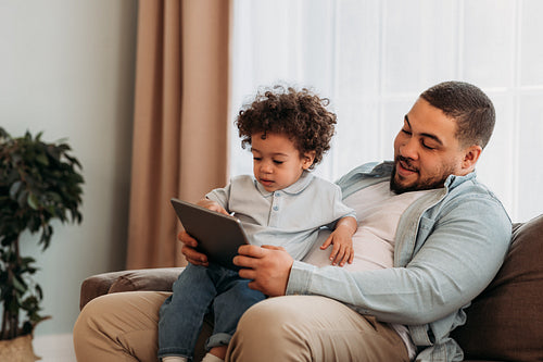 Young father and his little son using digital tablet