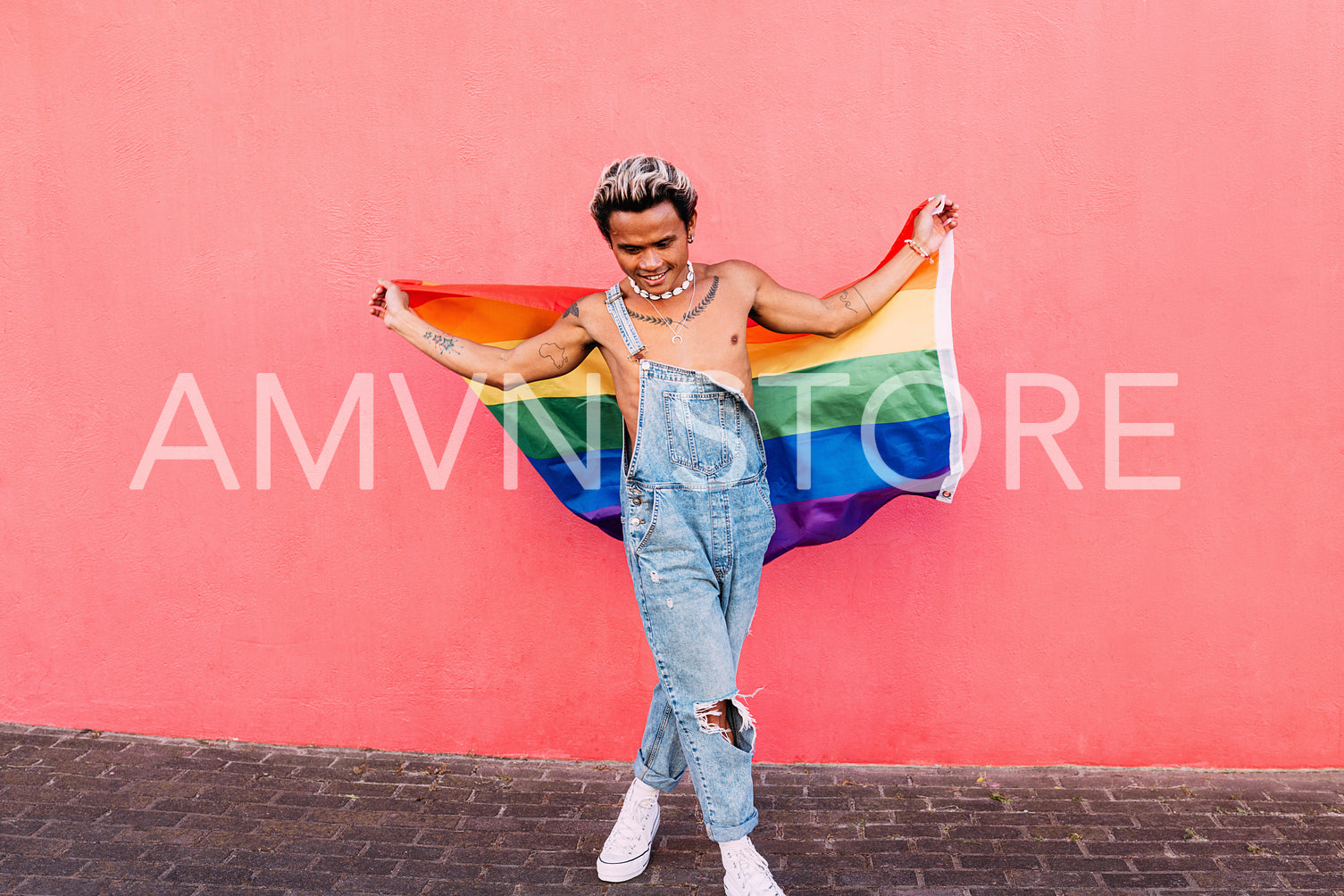 Young guy dancing with rainbow LGBT flag outdoors