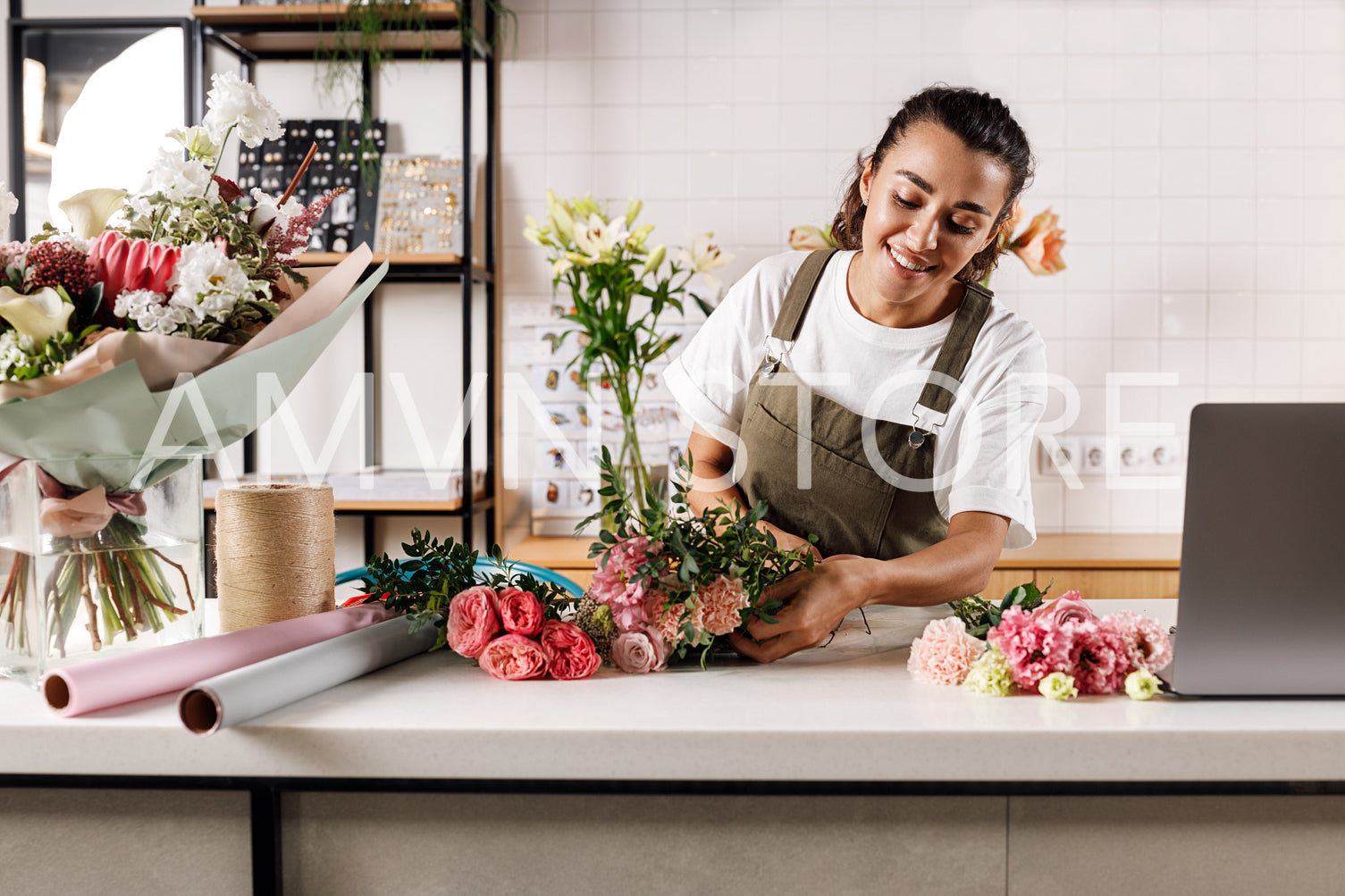 Female florist working at the counter. Beautiful woman preparing a bouquet at her small flower shop.	