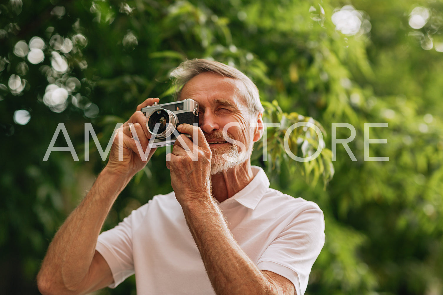 Senior man making photographs on film camera while walking outdoors	