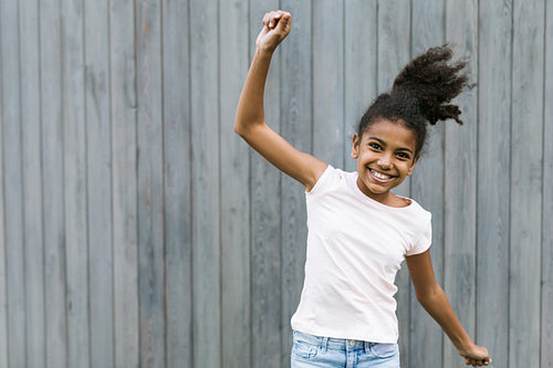 Happy girl jumping near a wall outdoors