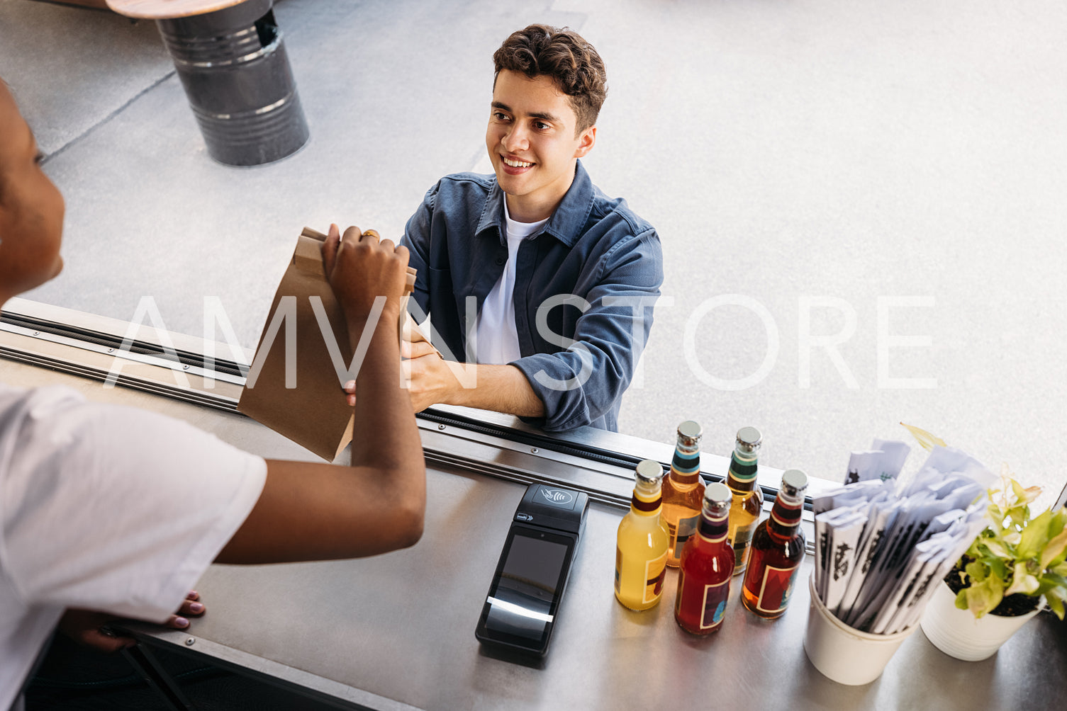 Young customer taking package with street food from an unrecognizable saleswoman at a food truck