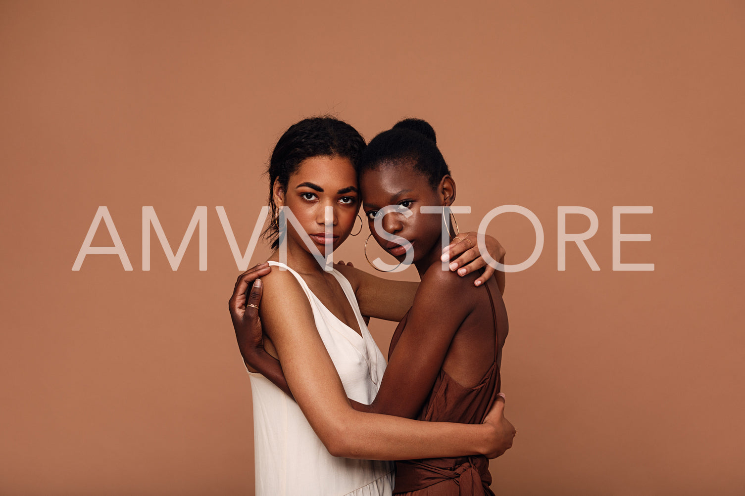 Two diverse women friends against brown background embracing each other	