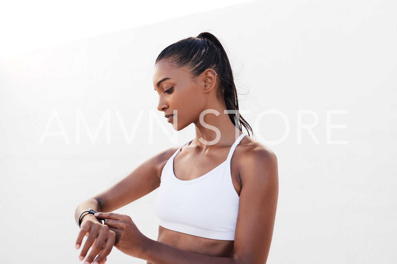 Fitness female in white sports attire adjusting smartwatch before a workout. Woman checking heart rate during training.