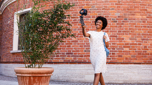 Young female vlogger filming a video while walking on city street