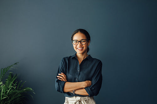 Portrait of a beautiful smiling businesswoman standing with crossed arms in living room