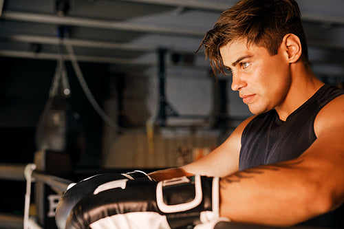 Side view of a boxer. Young athlete relaxing in ring.