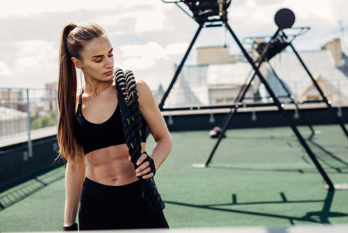 Woman looking down after intense physical training with battle ropes