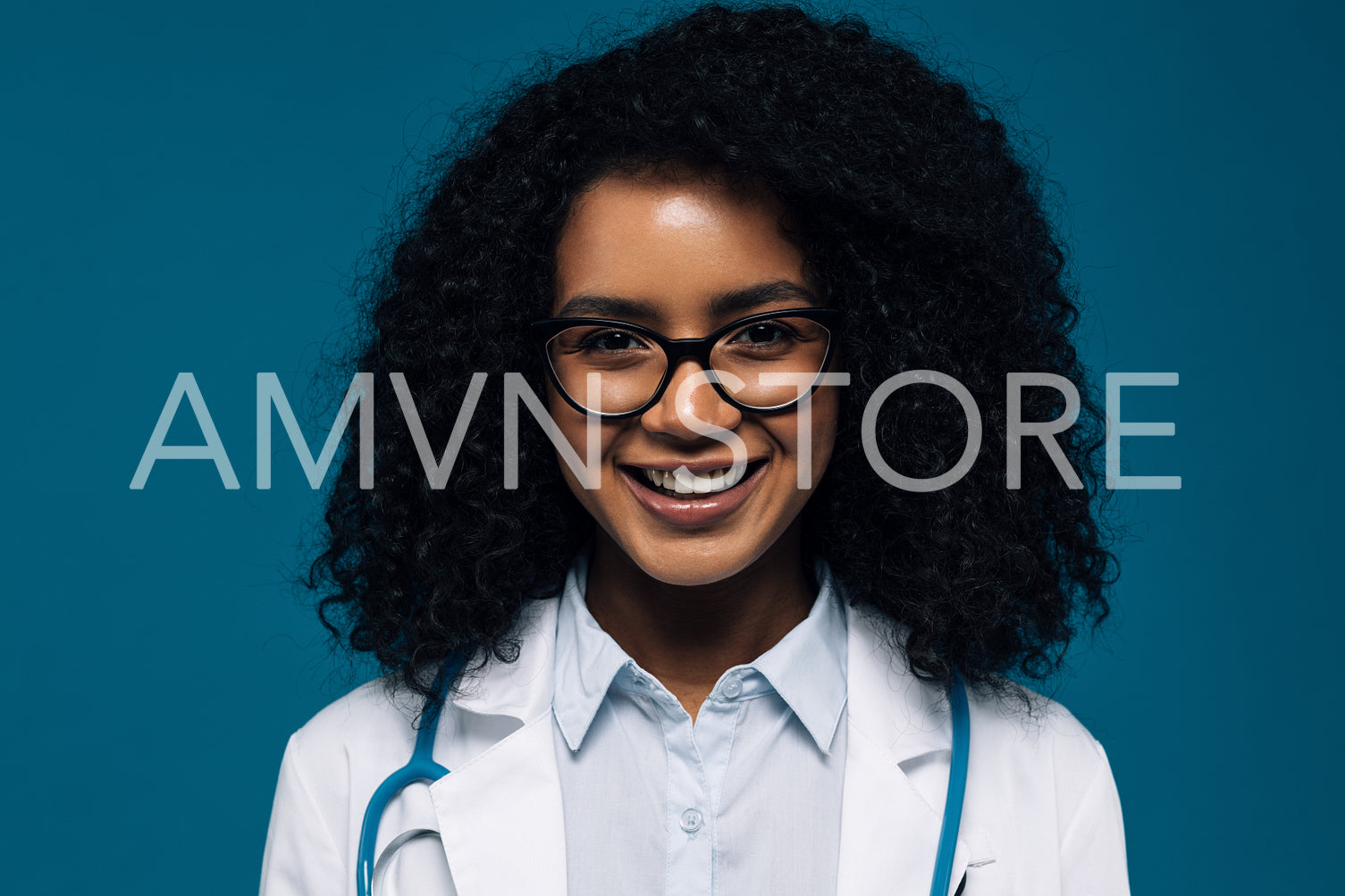 Close up of a beautiful smiling doctor in glasses looking at camera over blue background