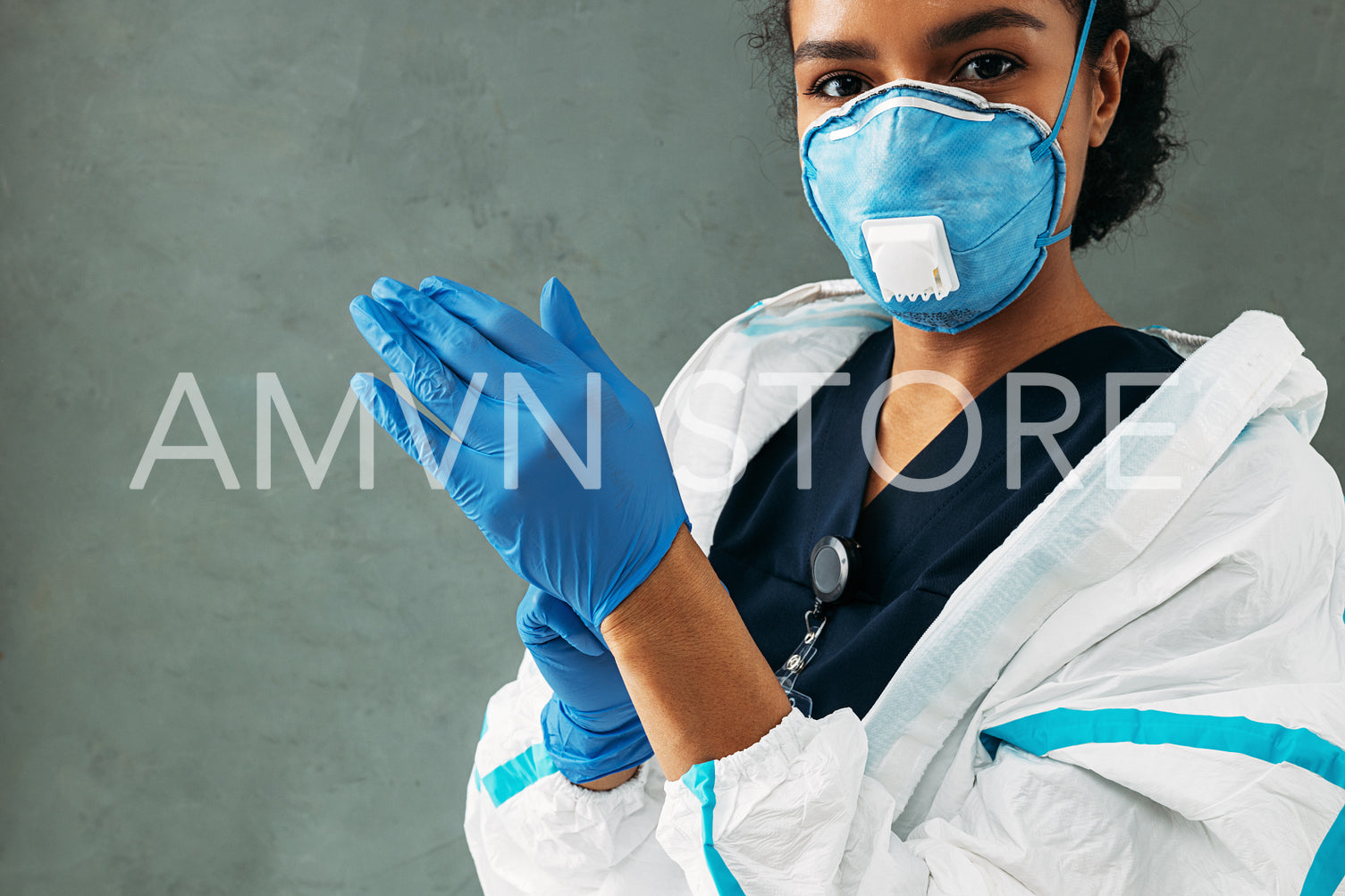 Young medical worker puts on surgical gloves looking at camera	