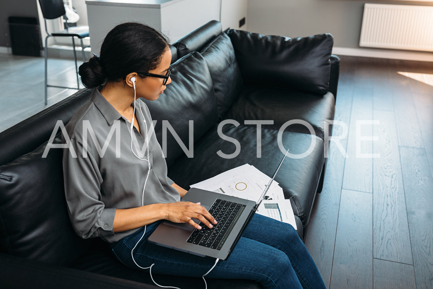 Young woman sitting in a living room in her apartment on a couch with laptop and looking on documents	