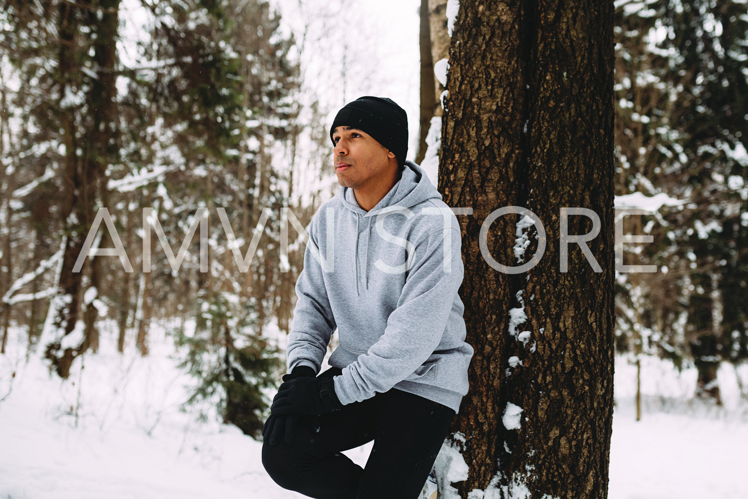 Young sportsman resting during workout, leaning on a tree	