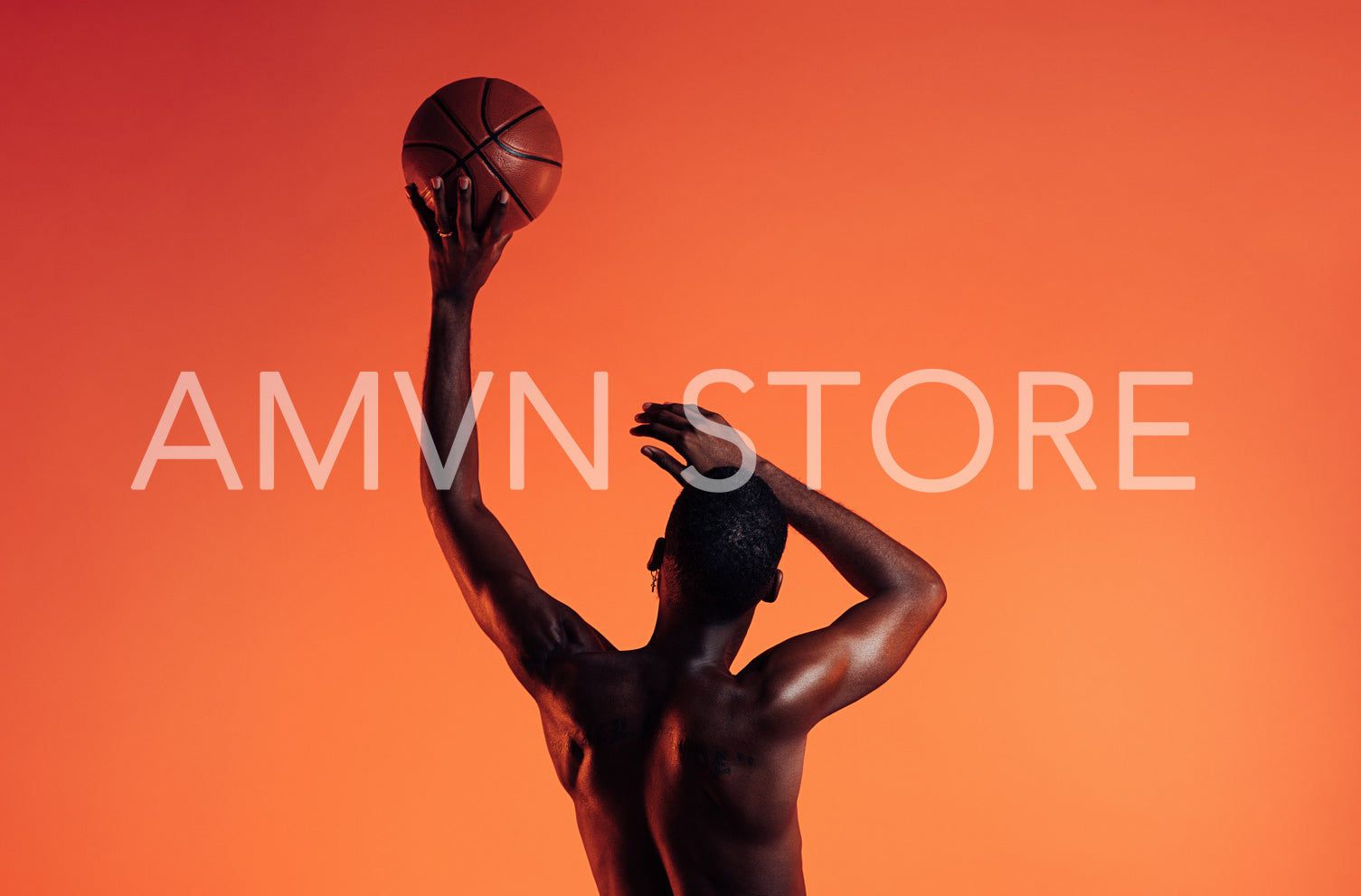 Rearview of basketball player against an orange background. Bare chest athlete holding a basket ball with one hand.