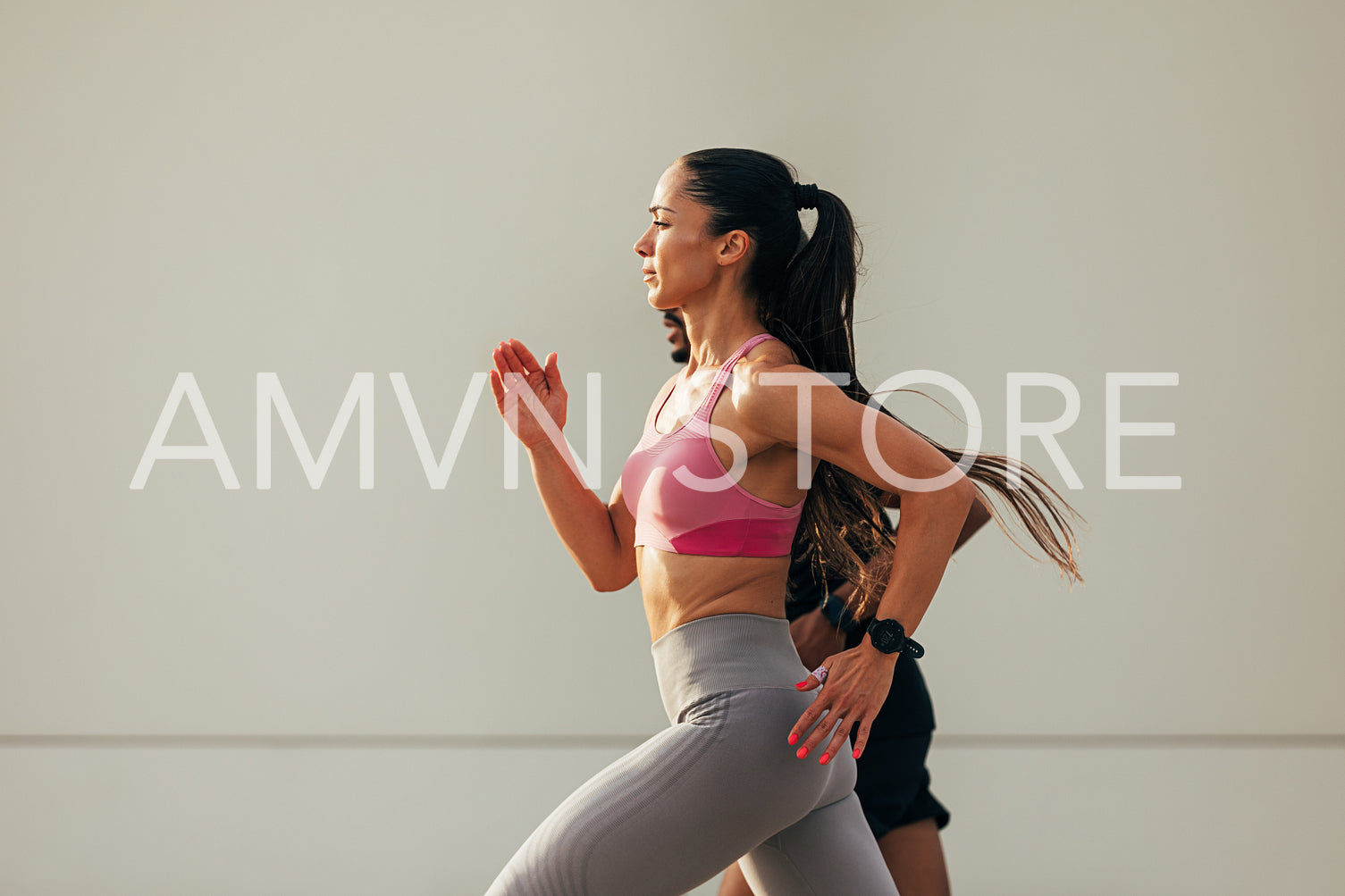 Side view of young woman runner at sunset on rooftop. Slim female sprinting with a workout buddy.