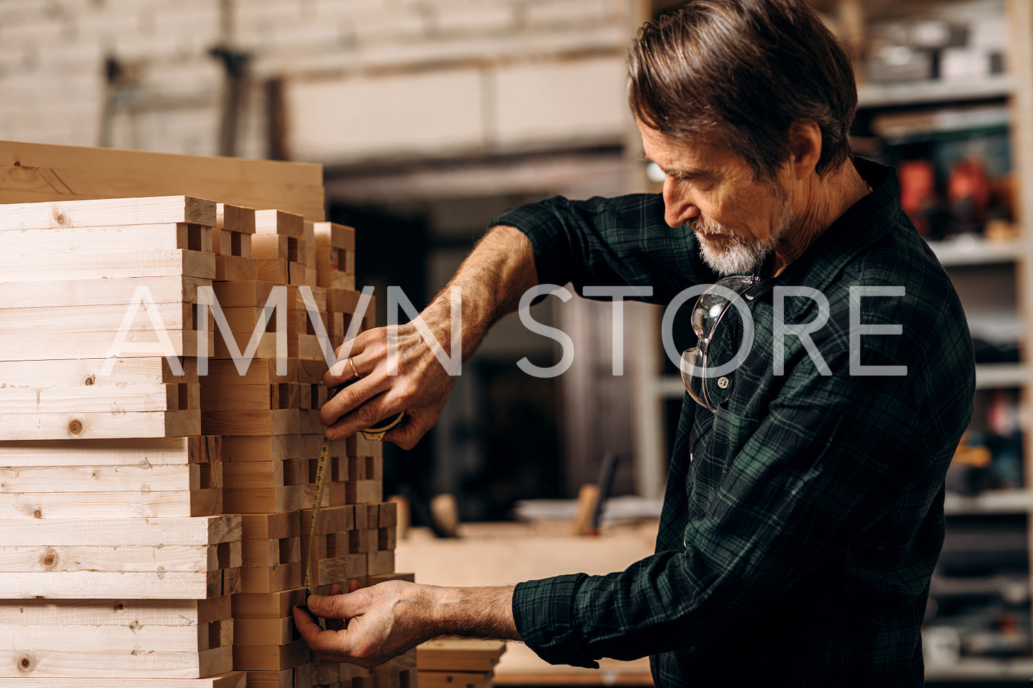 Senior carpenter using measuring tape on a bunch of wooden parts	