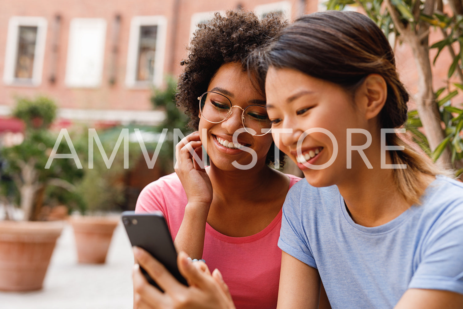 Two female friends live streaming from outdoor cafe	