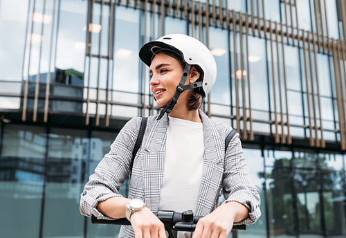 Portrait of a confident businesswoman in safety helmet standing outdoors with electric scooter