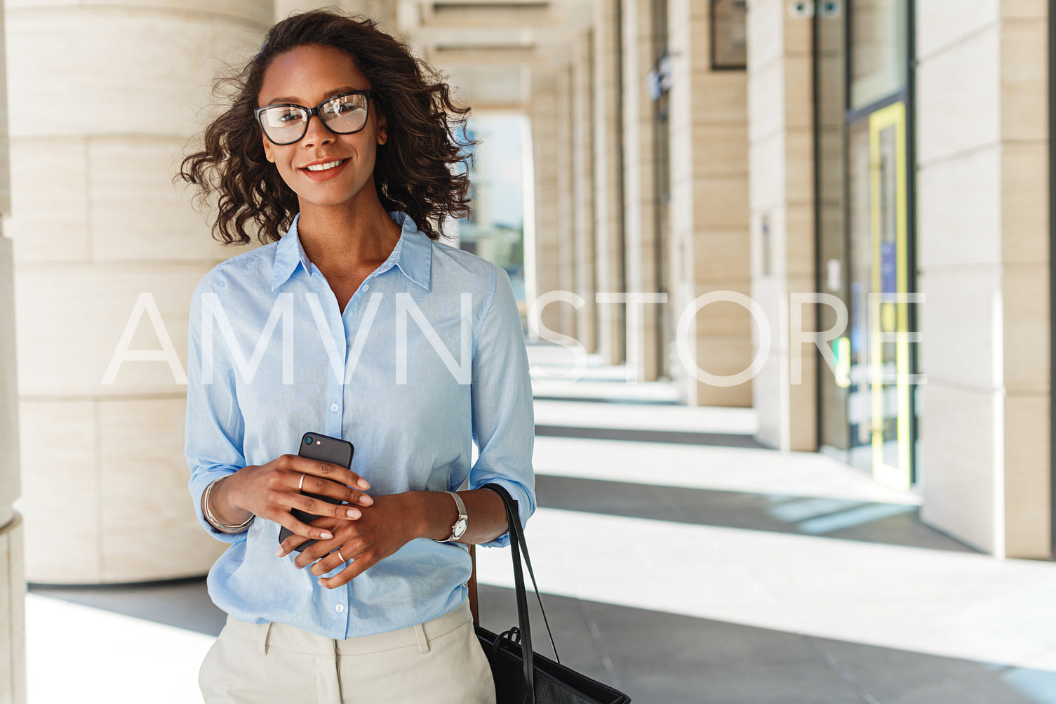 Smiling woman holding a cell phone with office building on background	