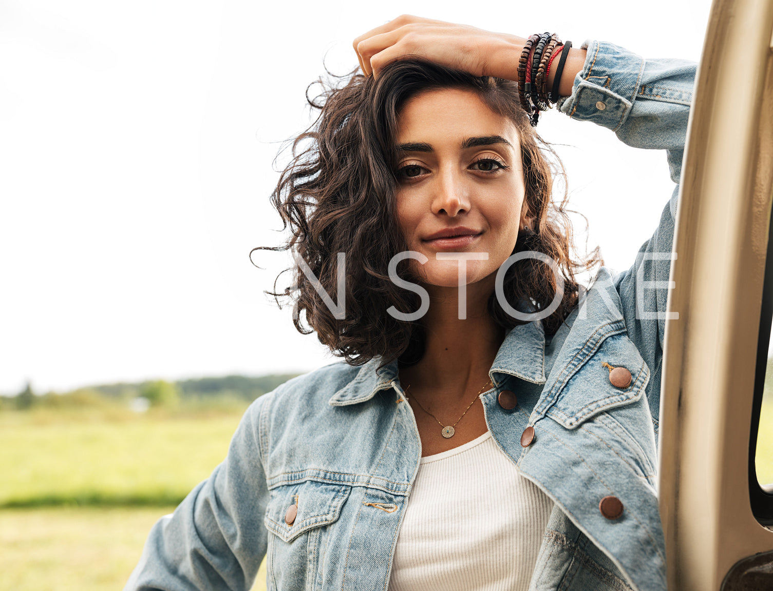 Portrait of young woman leaning car door looking at camera