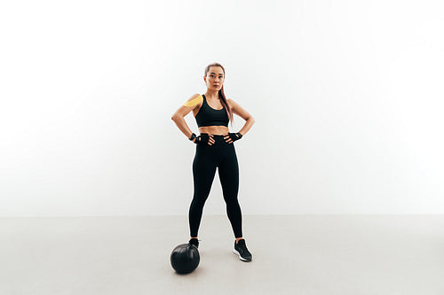 Female athlete wearing gloves resting after exercises with medicine ball