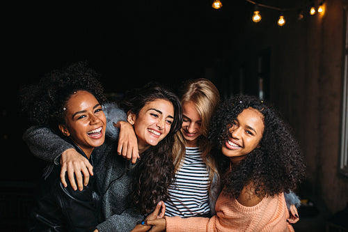 Four beautiful women looking at camera, standing outdoors at night