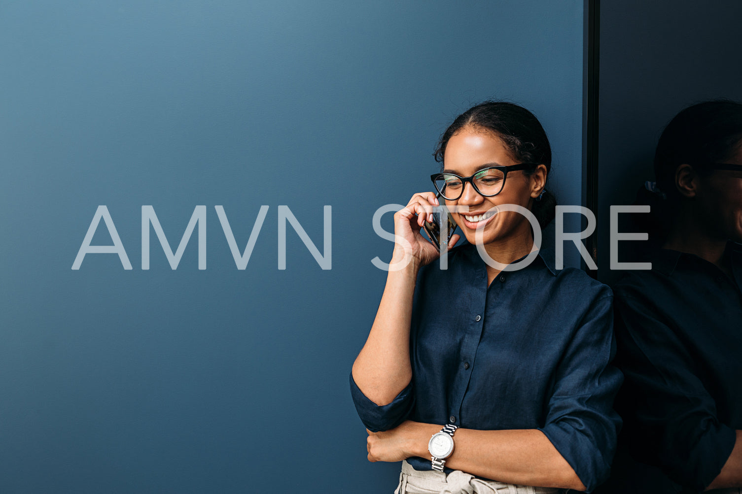 Smiling woman making phone call from home standing at wall	