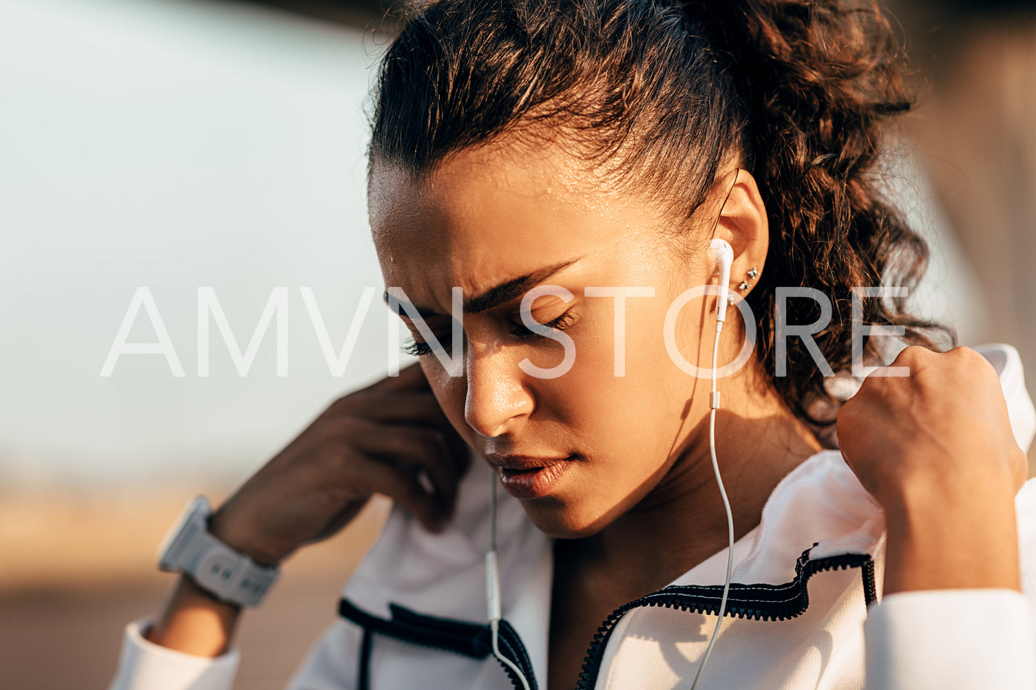 Tired sportswoman wearing a hoodie jacket. Young female athlete taking a break during workout with closed eyes.