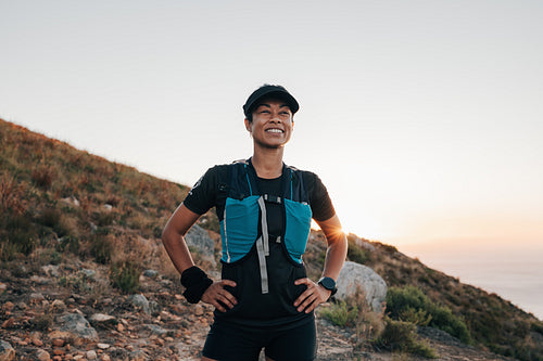 Smiling woman hiker relaxing during hike holding hands on waist