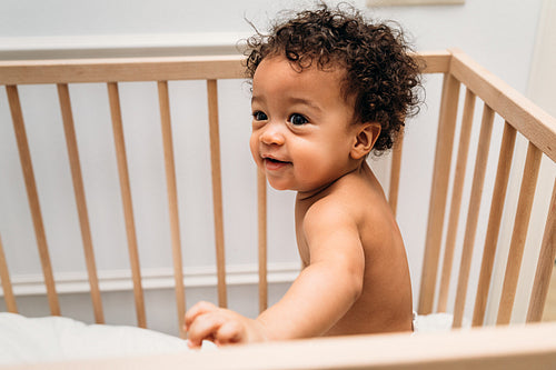 Portrait of cute baby boy standing in crib at home