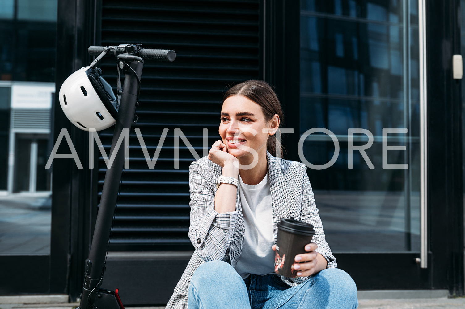 Beautiful smiling businesswoman with coffee sitting on an electric scooter at building looking away