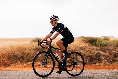 Side view of professional woman cyclist riding her bike outdoors