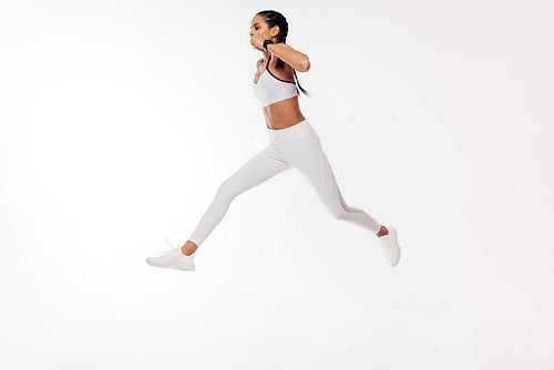 Woman athlete jumping on a white background in studio