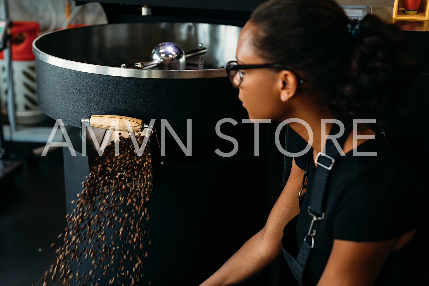 Young entrepreneur sitting at roasting machine, controlling a prepared roasting beans	