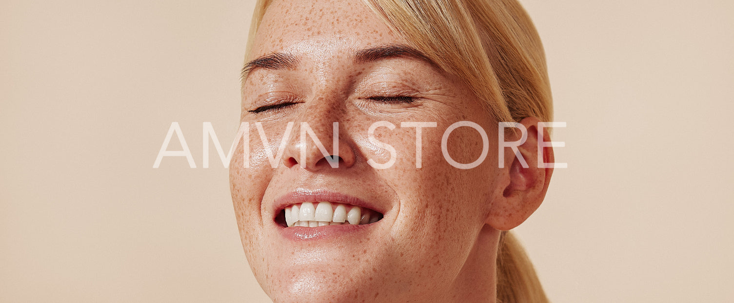 High-detailed portrait of a smiling female with freckles. Happy blond with closed eyes and freckled skin.