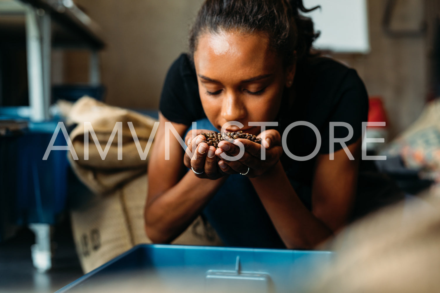 Woman examining and smelling the aroma of coffee beans on her hands	