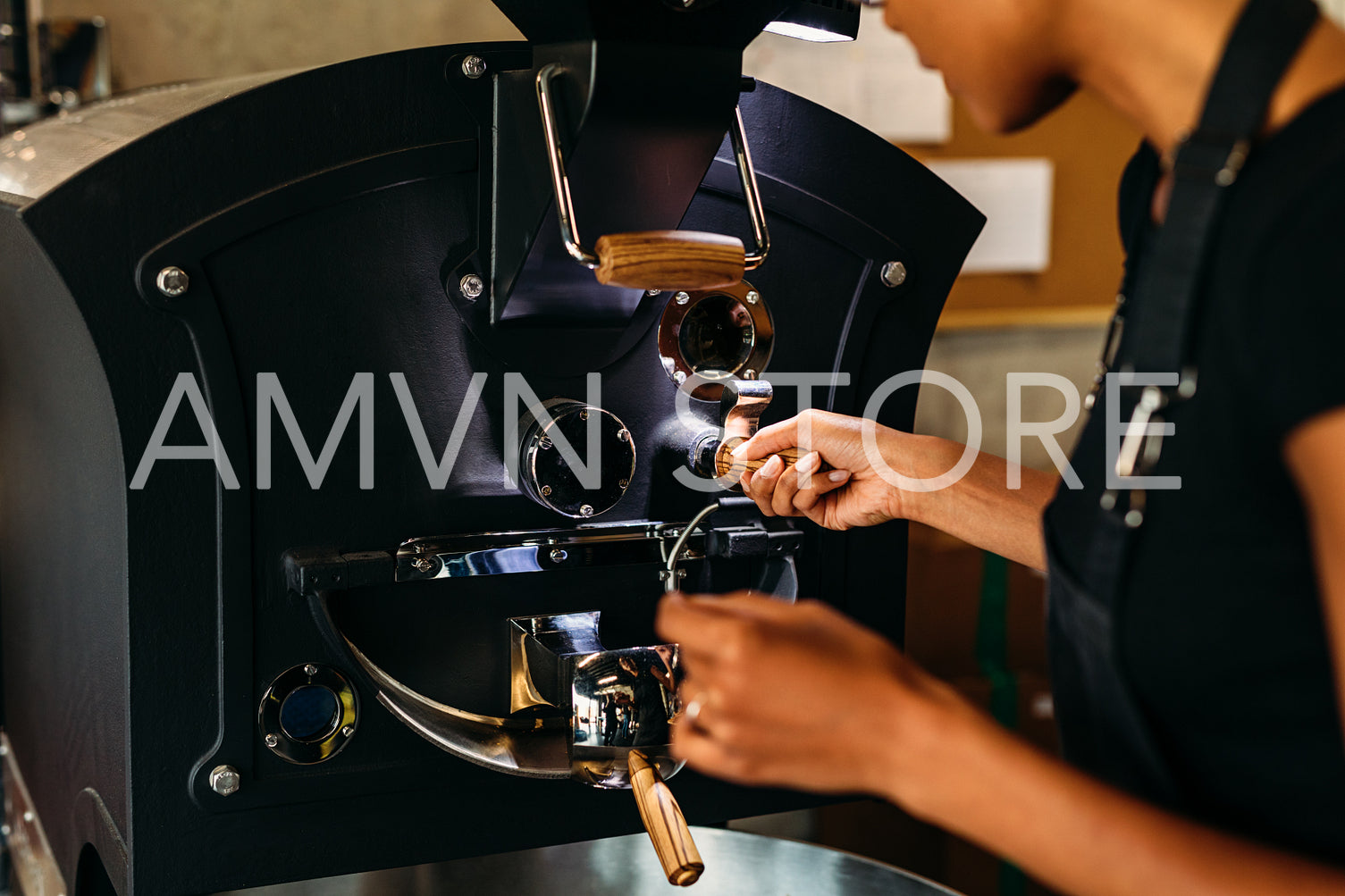 Unrecognizable woman controlling a roasting coffee process, operating a machine	