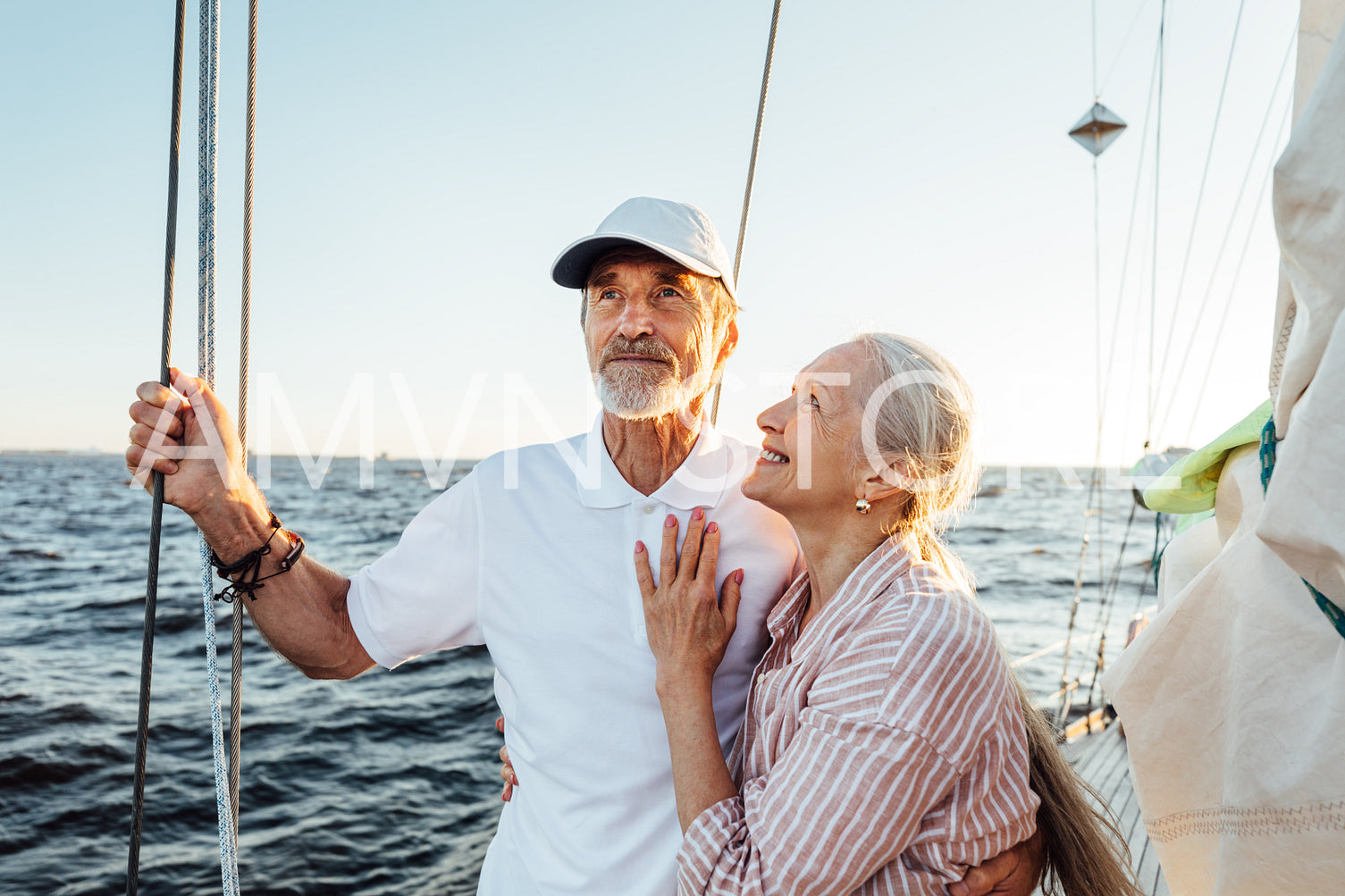 Smiling mature woman looking at his husband while standing at sail on a yacht	