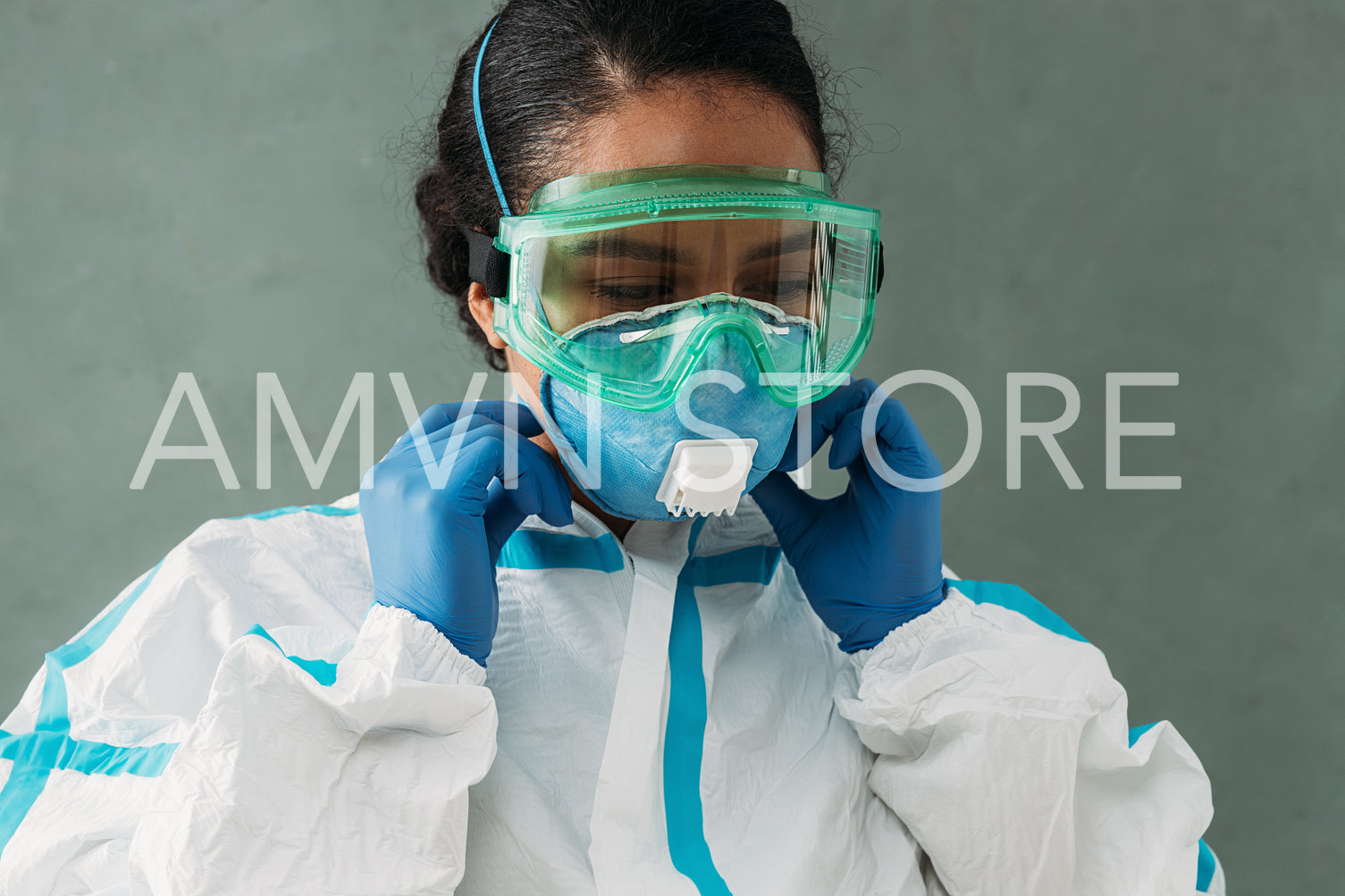 Young doctor in protective glasses and suit adjusting face mask	