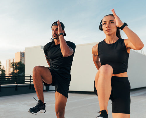 Two athletes in black sportswear practicing together on the roof