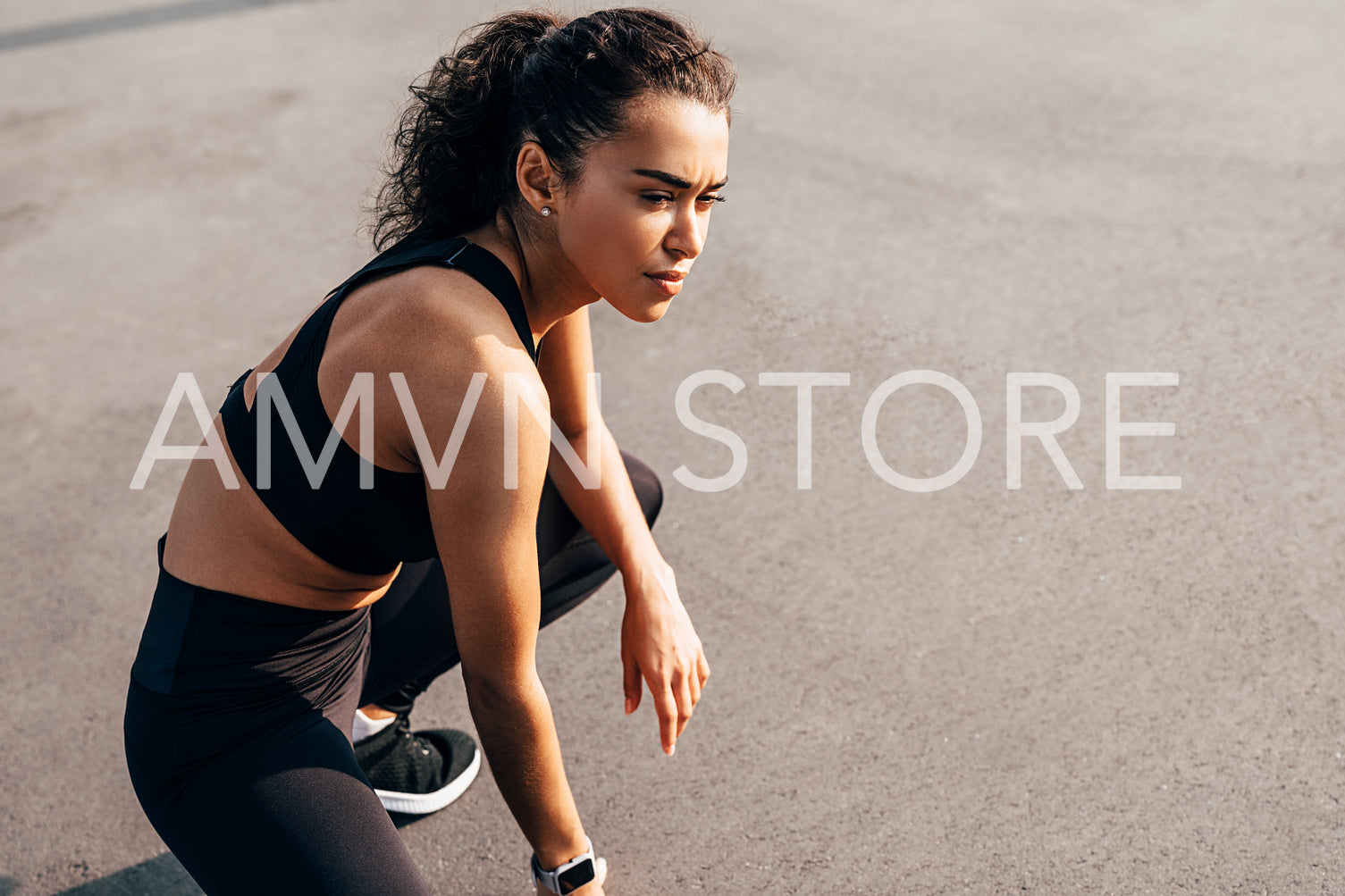 Side view of a muscular sportswoman sitting outdoors resting during training and looking away	