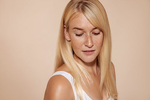 Portrait of a woman with blond hair and freckles looking down wh