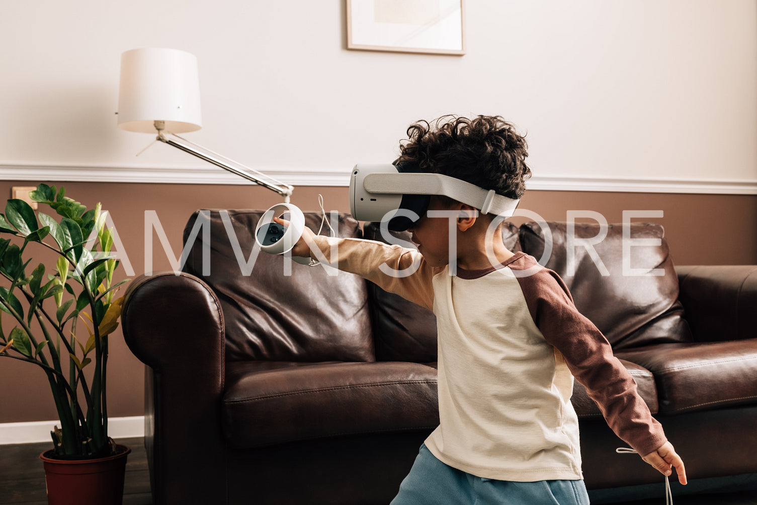 Little boy in VR goggles in living room. Kid enjoying virtual reality game using a controller.	