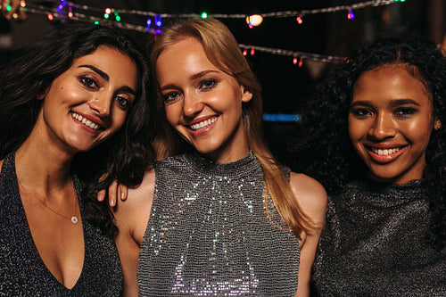 Outdoor portrait of young women standing in front of christmas light at night