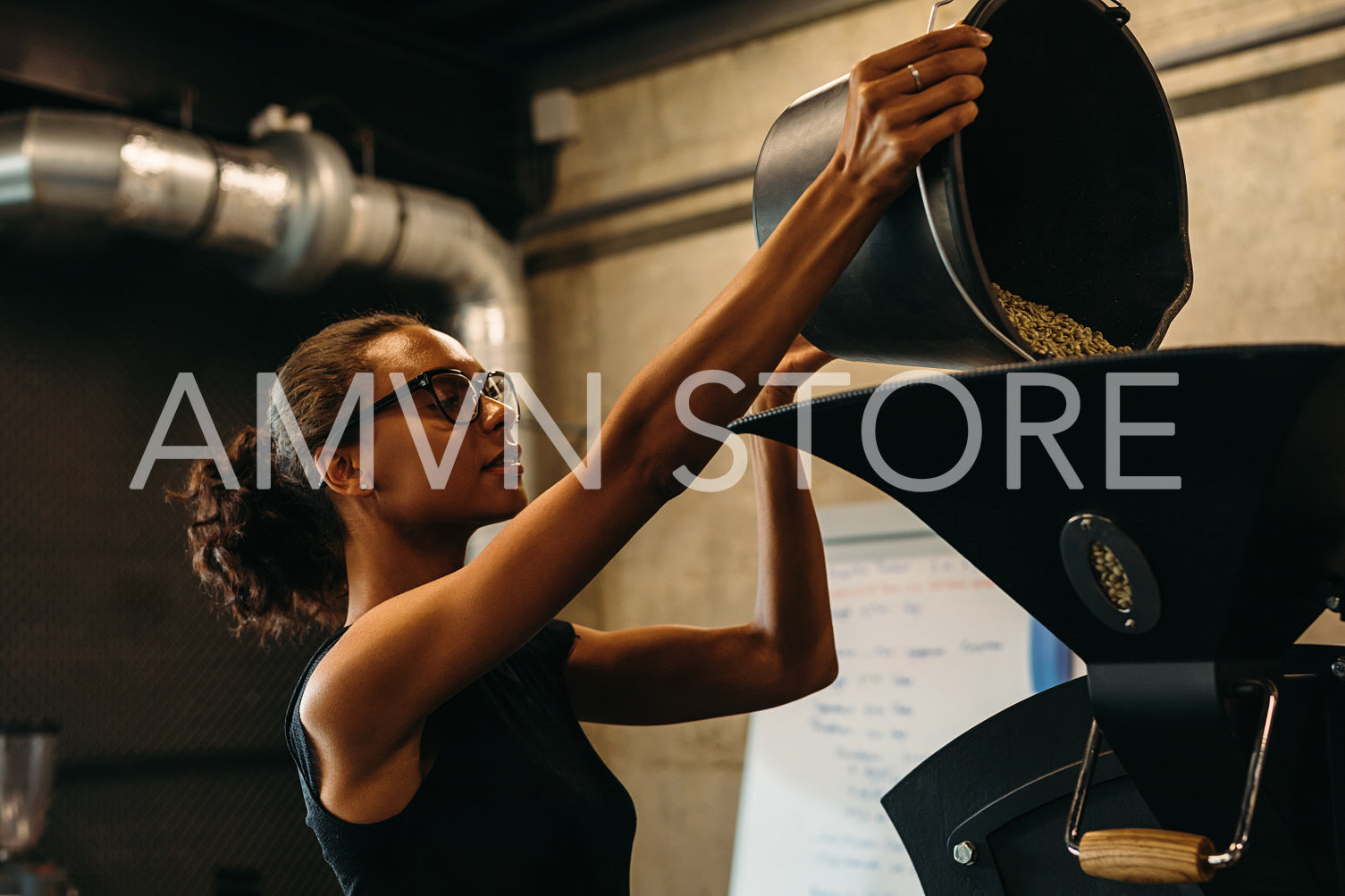 Woman putting coffee beans in the coffee roasting machine	