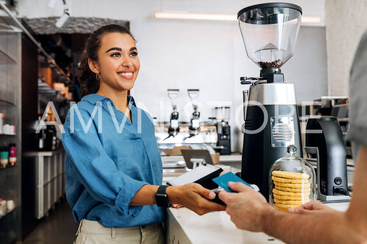 Female coffee shop owner holding a POS terminal while unrecognizable customer paying cashless