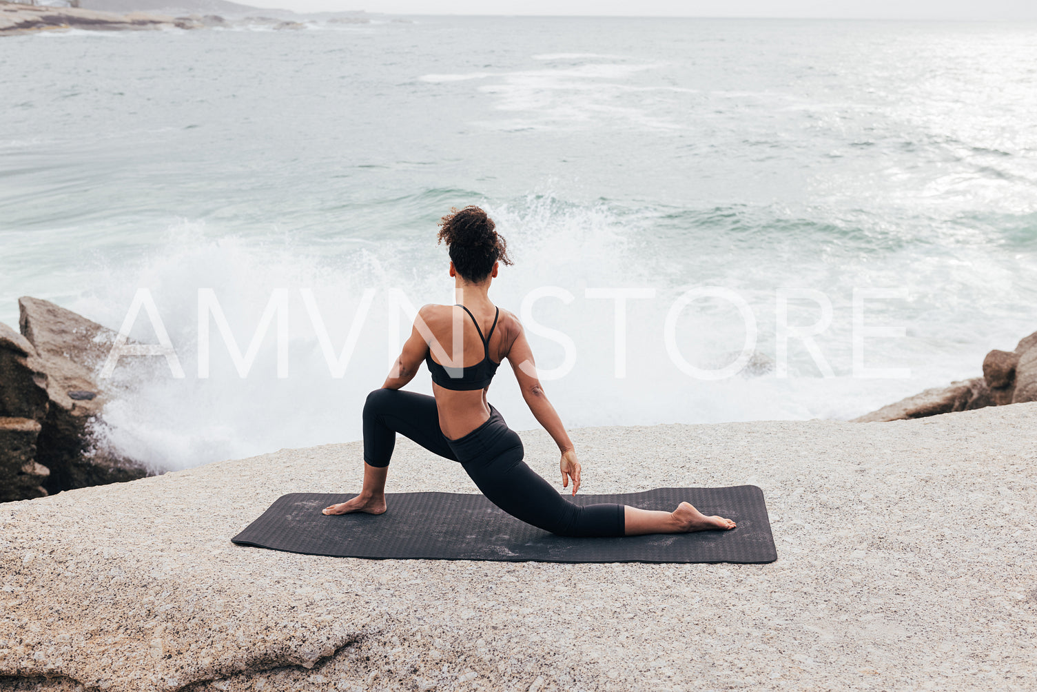 Young woman practicing yoga on mat by ocean at evening