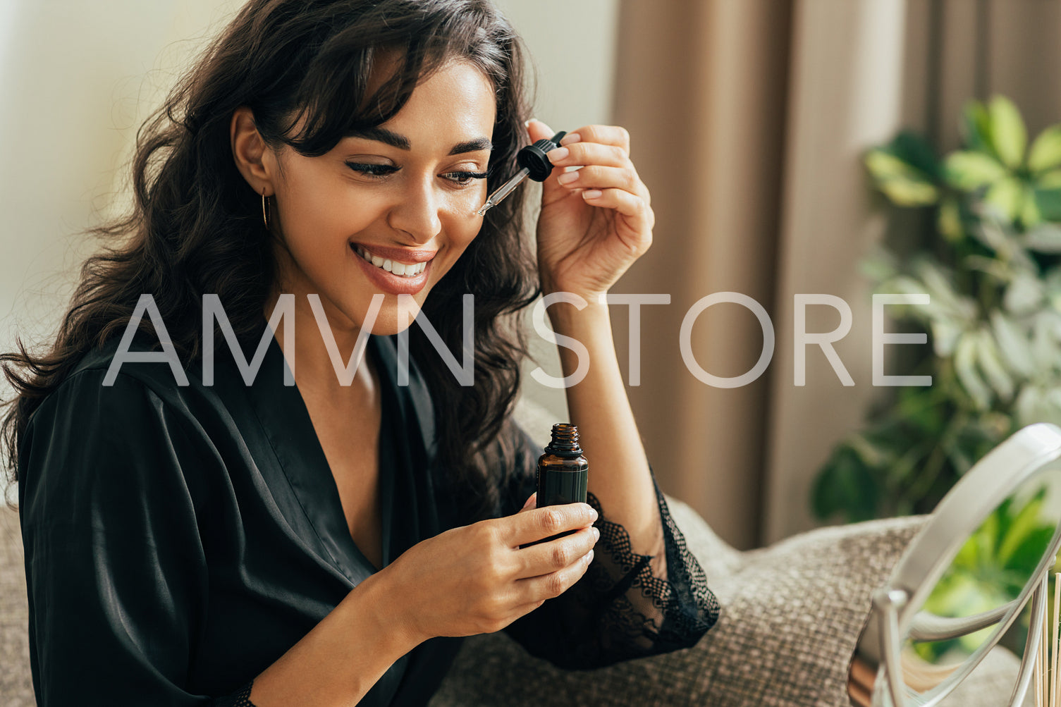 Young smiling woman sitting on a couch applying hyaluronic acid on a face	