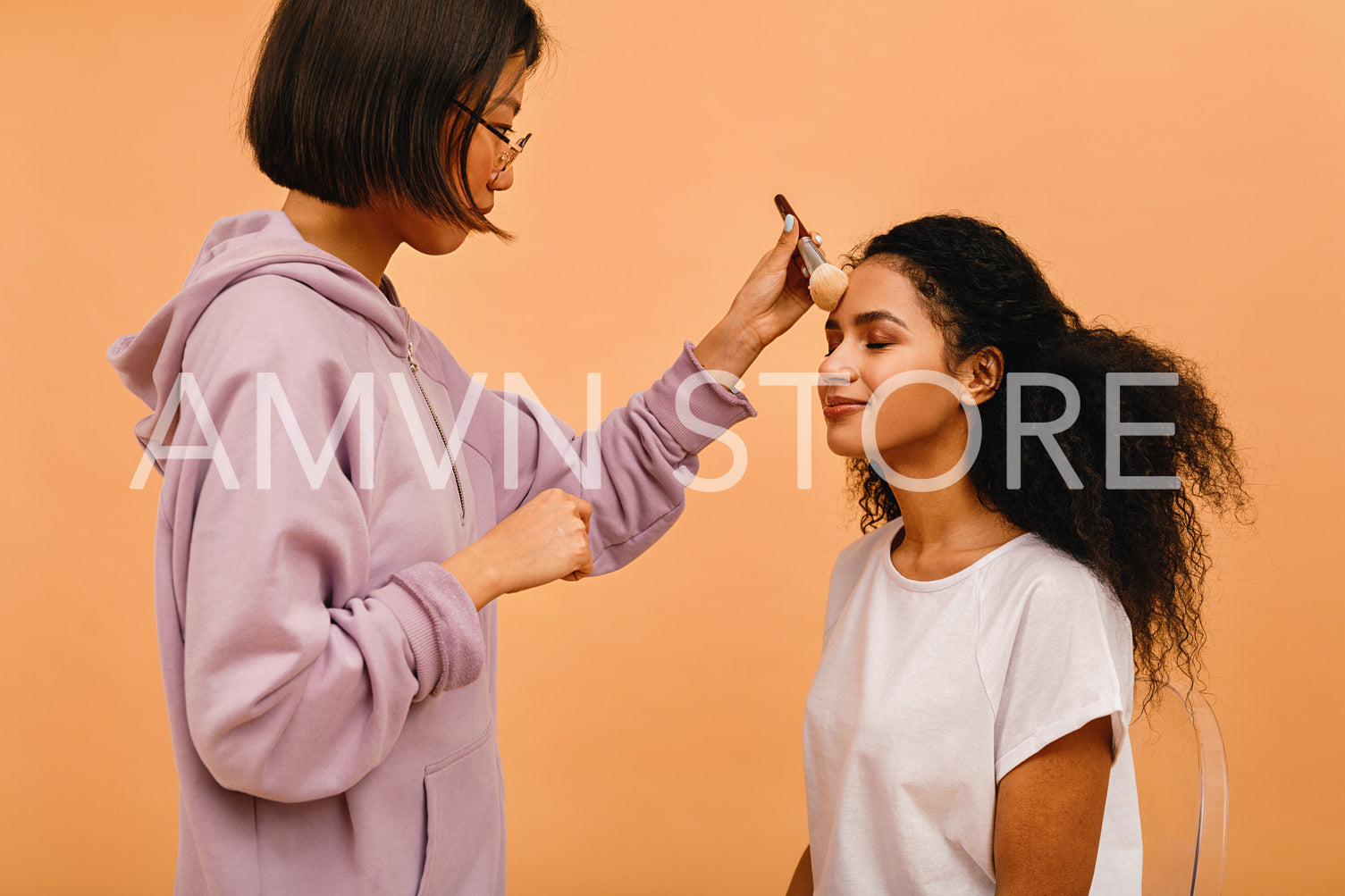 Professional make up artist applying tonal powder on model in studio	
