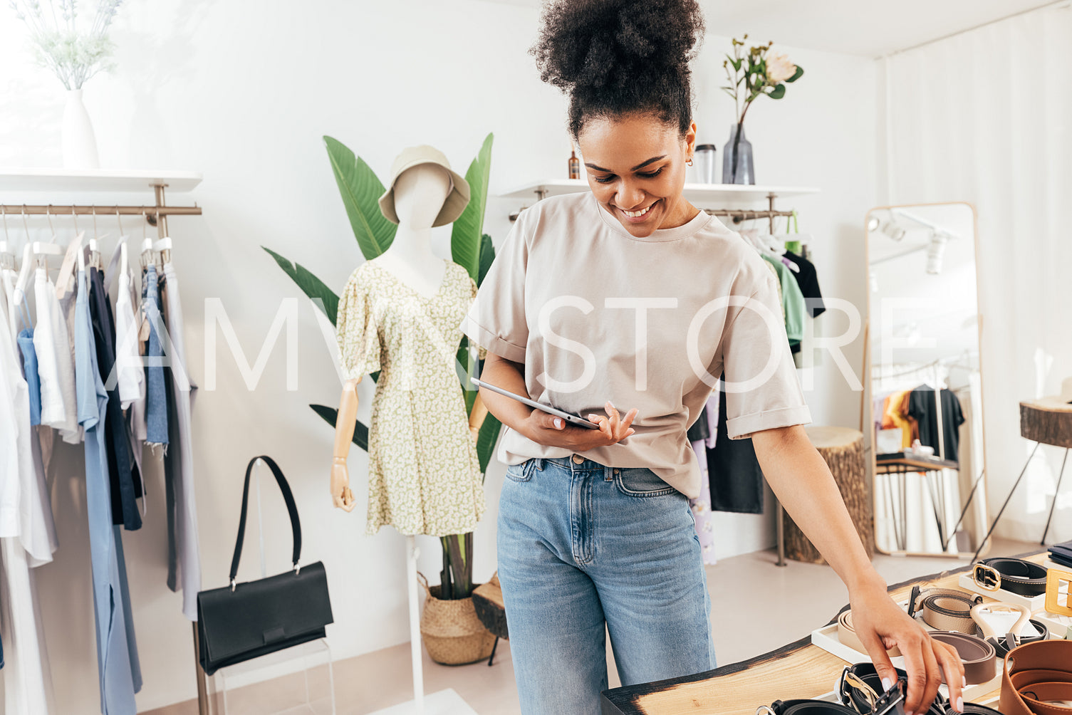 Young saleswoman using a digital tablet at store. Business owner working with merchandise in her retail shop.