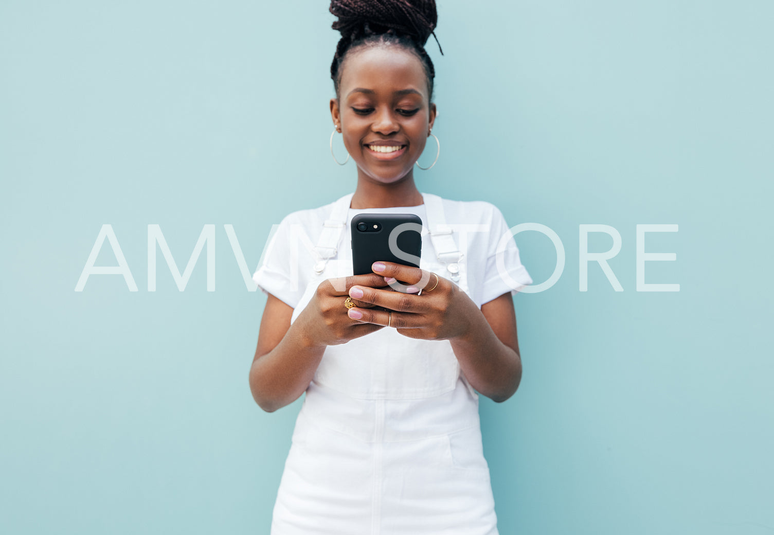 Close up of a positive young female typing on smartphone at blue wall